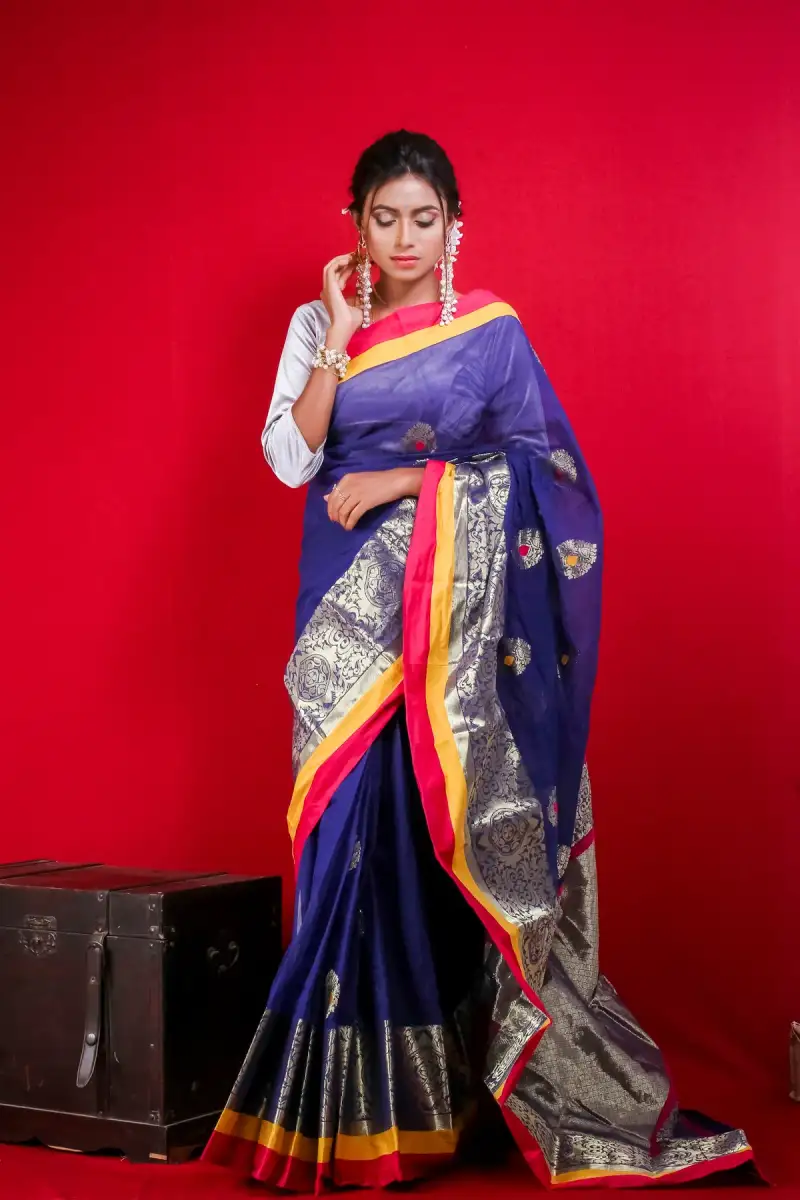 Woman in a royal blue silk saree with a red and gold border