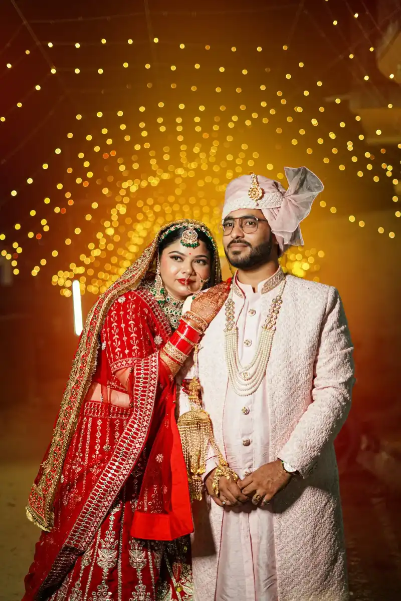 Bride and groom in traditional wedding outfits under warm fairy lights