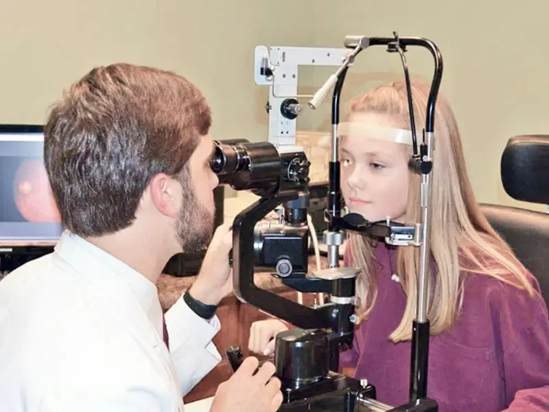 Optometrist examining a patient's eyes with a slit lamp