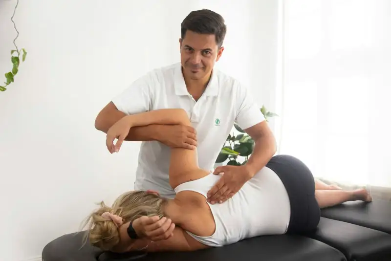 Physiotherapist treating a patient's shoulder on a treatment table